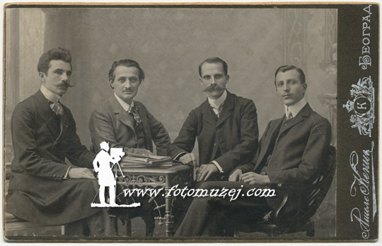 Četvorica muškaraca za stolom sa knjigama (Atelje Kenig)