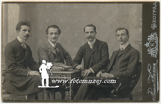 Četvorica muškaraca za stolom sa knjigama (Atelje Kenig)