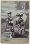 Dve devojčice sa šeširima i suncobranima